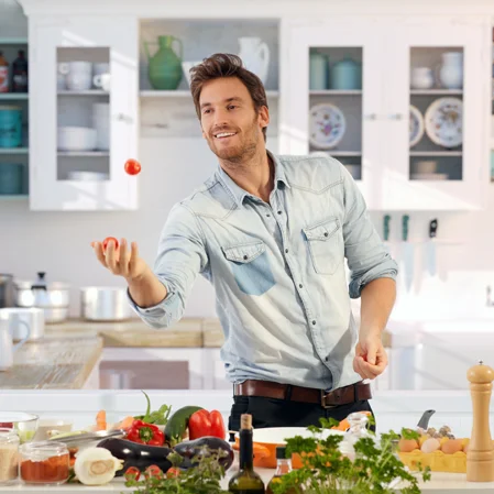 A happy man cooking dinner in the kitchen using all natural and clean ingredients