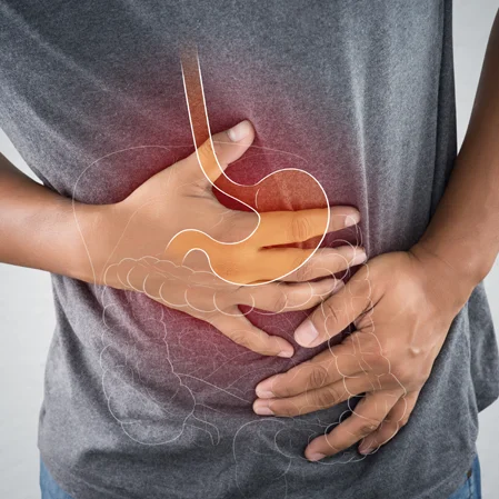 A patient clutching their abdomen in pain. An inflamed image of the digestive system is superimposed on the image