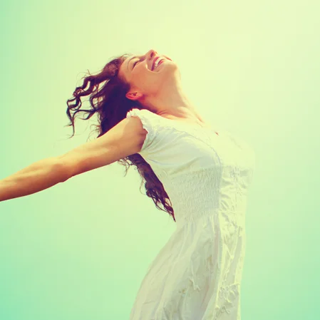 A woman throwing her head and arms back in the sunshine