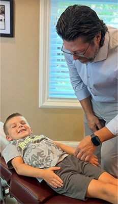 Chiropractor Southern Pines NC Thomas McKay Jr. With Child Patient HP Chiropractor Thomas McKay Jr. With Smiling Young Patient