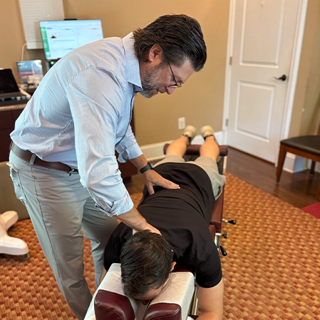 Thomas McKay Jr. Adjusting A Patient's Back Lying On A Chiropractic Table